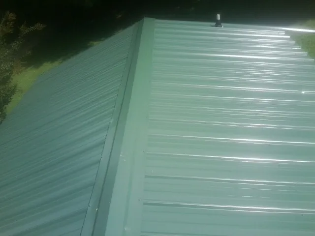 New green metal panels meeting at the ridge of a roof — Flat Roof Repair work by our crew in Mount Royal