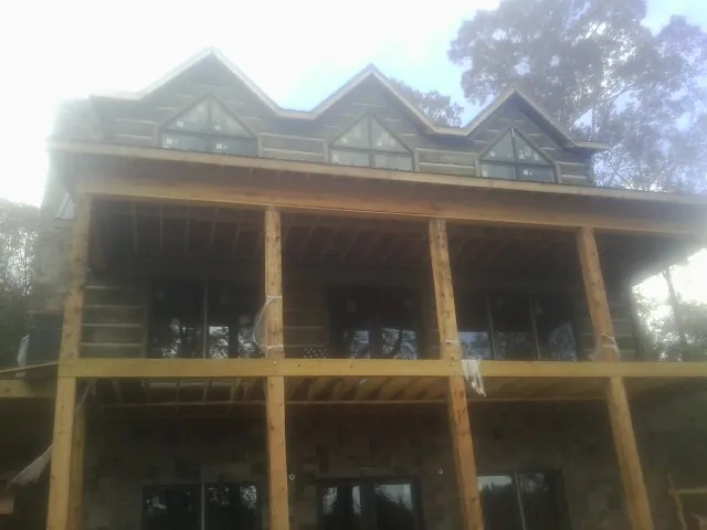 Dormers and porch framing on a large log home under construction — Roof Coating work by our crew in Mount Royal