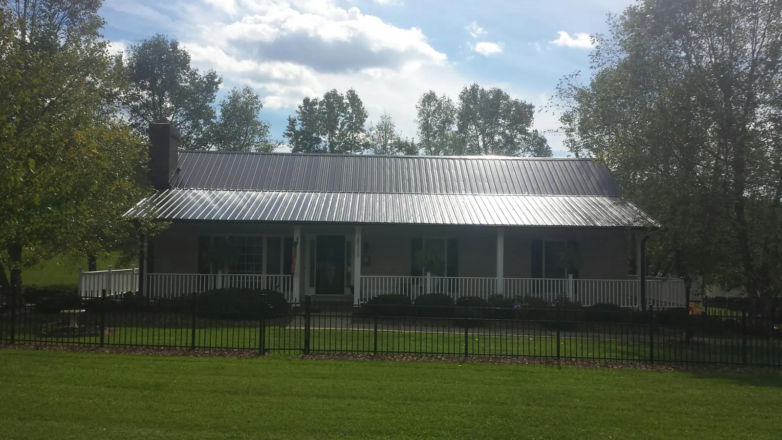Gray metal roof on a brick ranch with a full width front porch — Gutter Guard Installation work by our crew in Mount Royal