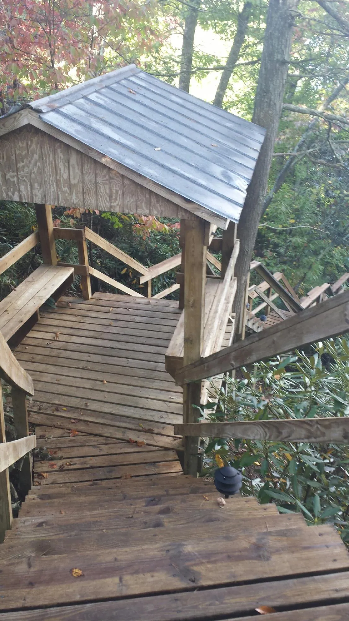 Metal roofed shelter over wooden steps on a wooded walkway — Skylight Repair & Installation work by our crew in Mount Royal