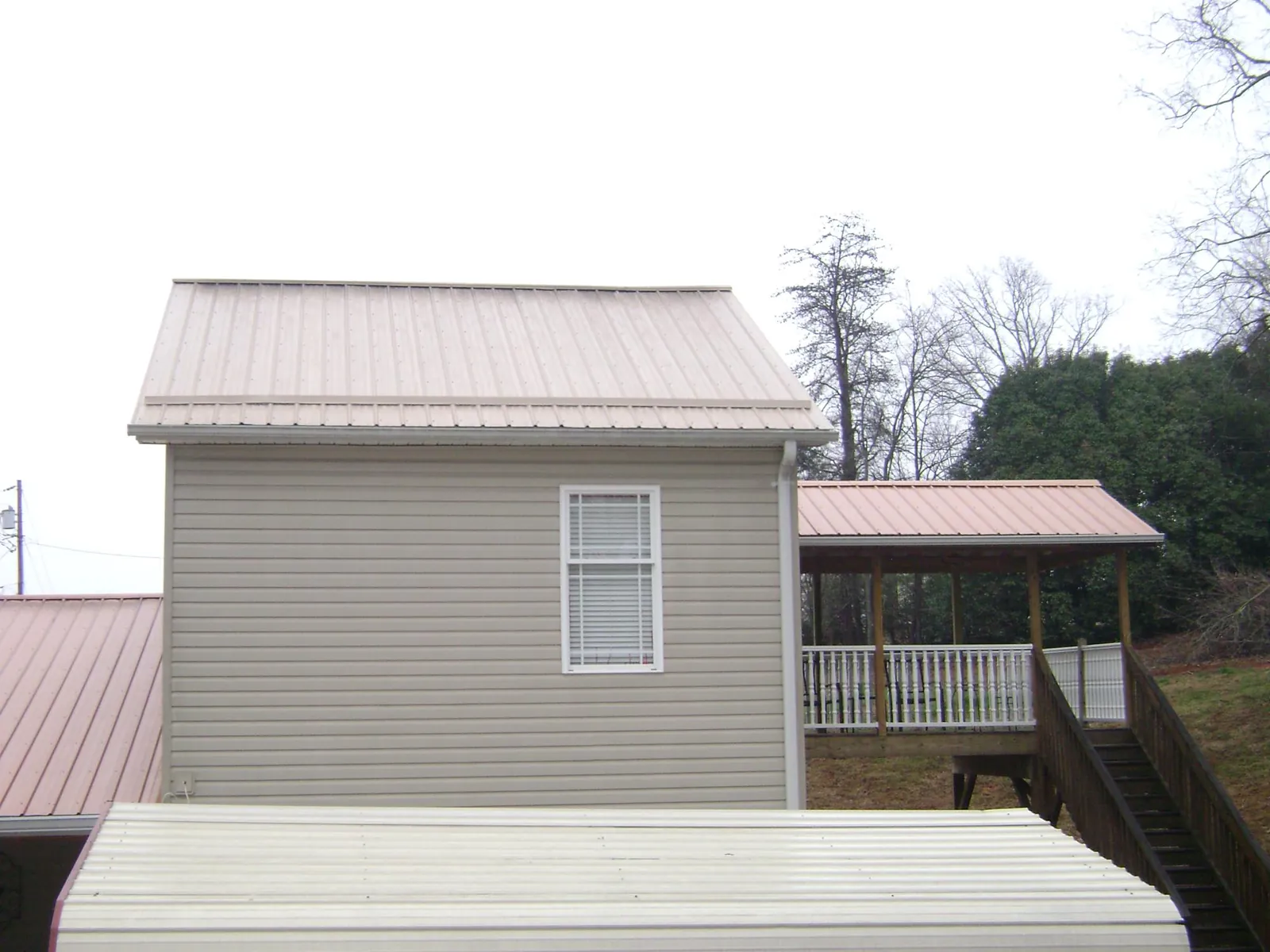Tan metal roofs on a two story addition and attached porch, from a Roof Replacement job in Mount Royal