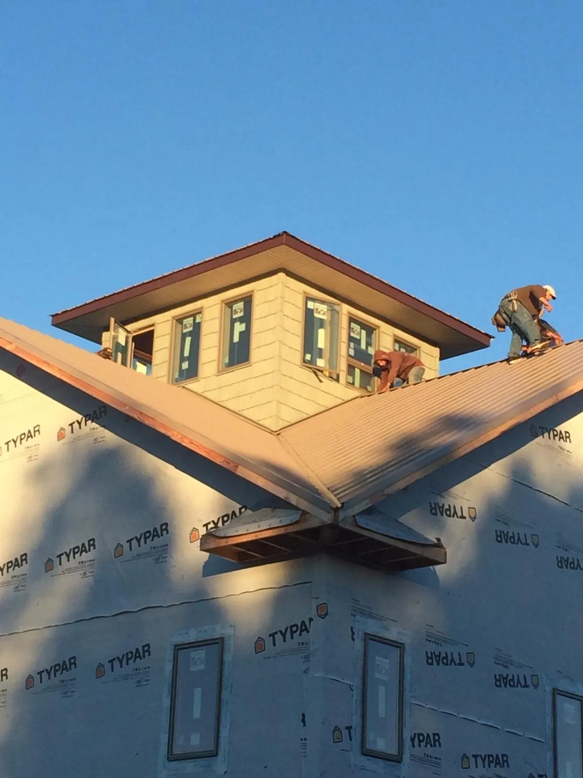 Roofers working around a rooftop cupola on a new metal roof at sunset — Roof Waterproofing in Mount Royal by Roofing Brothers